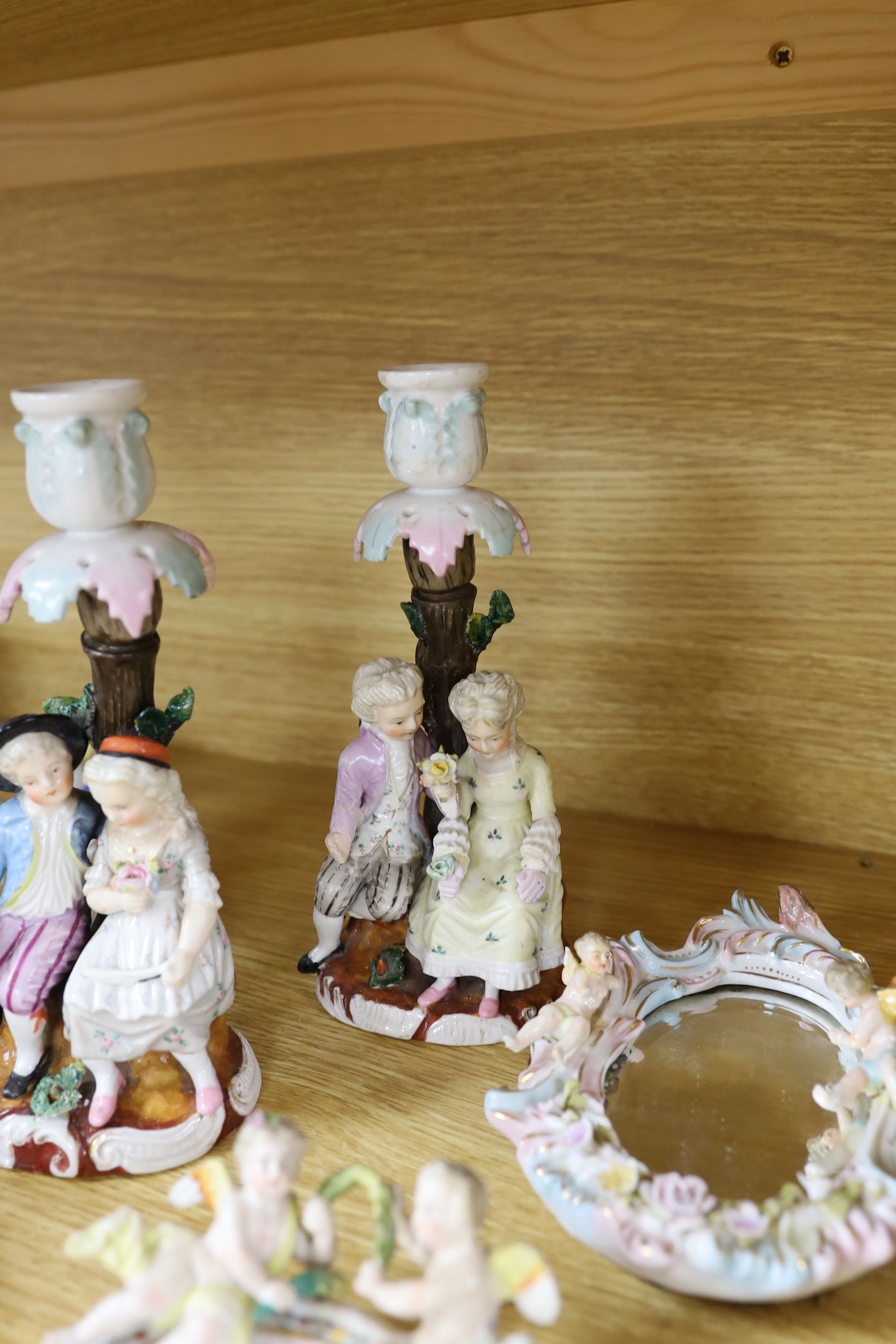 A pair of 19th century continental porcelain figural candlesticks and a group of four similar frames